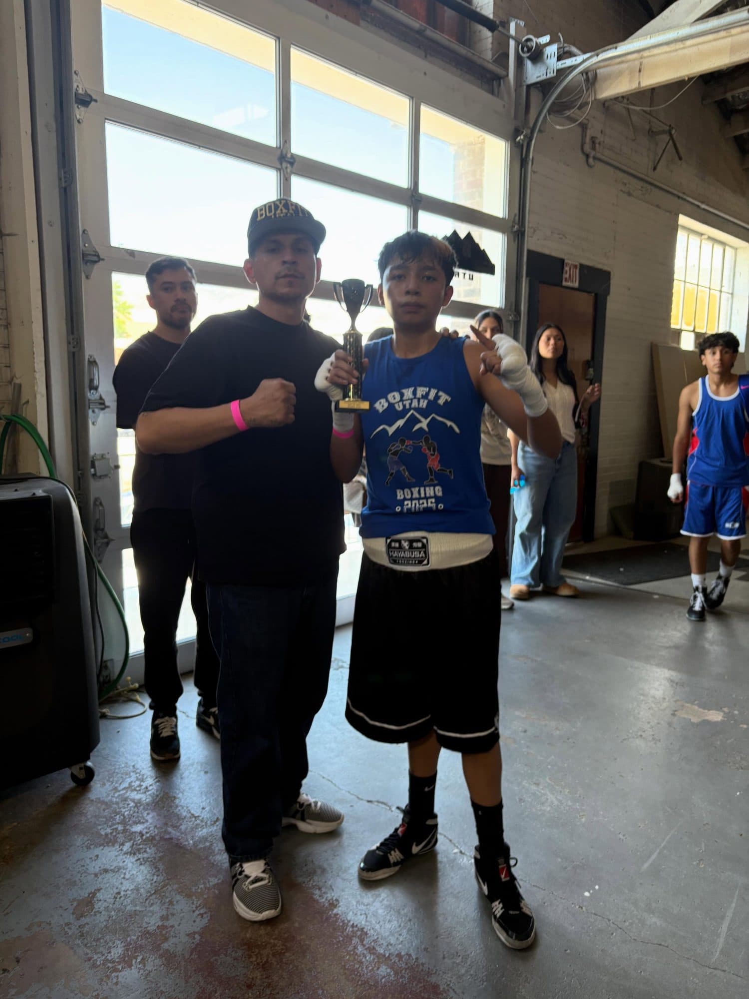 Coach Pablo and a young BoxFit fighter holding a trophy after a competition